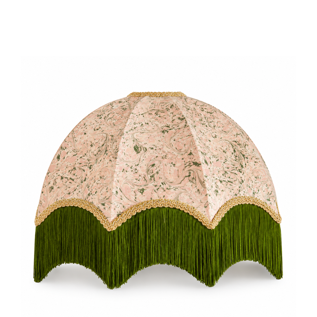 A dome-shaped lampshade featuring a light pink floral patterned fabric upper section, a green fringe bottom, and a gold scalloped trim separating the two sections.