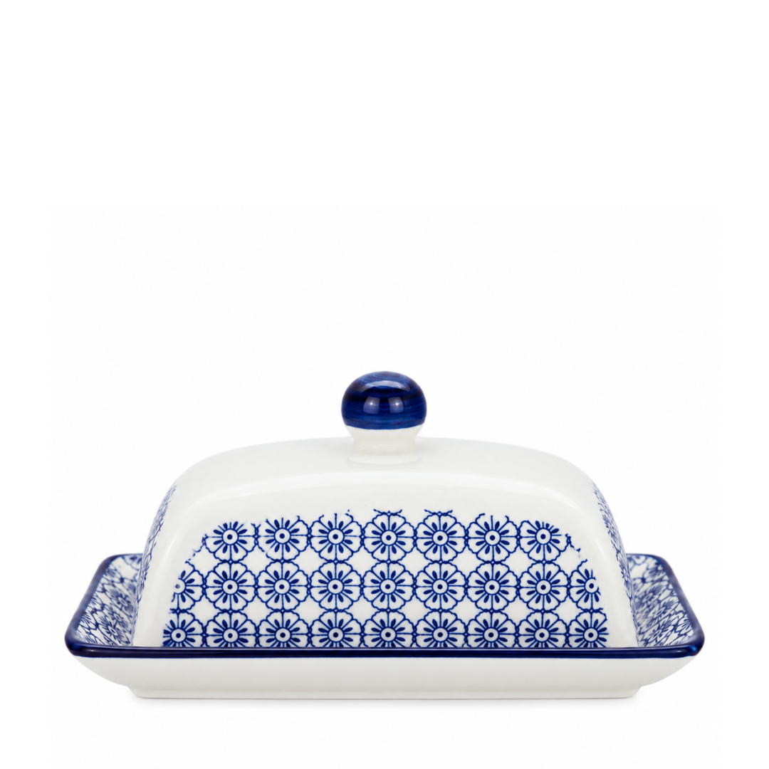 A white ceramic butter dish with a matching lid, decorated with a blue floral pattern and featuring a blue knob on top, set against a plain white background.