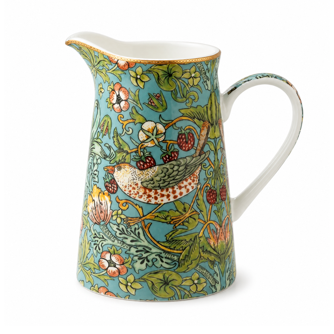 A ceramic pitcher with a William Morris-style floral and bird pattern on a turquoise background, featuring a white handle and interior, set against a plain white background.