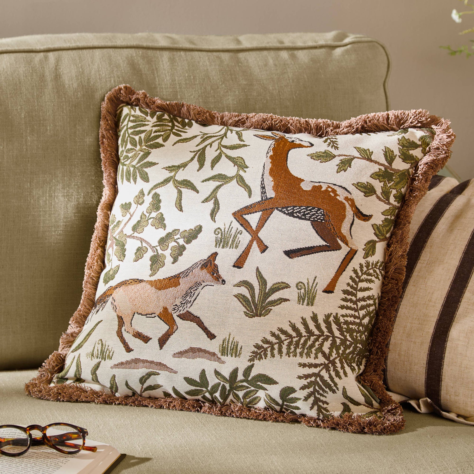 Decorative pillow with animal and nature pattern on a beige couch