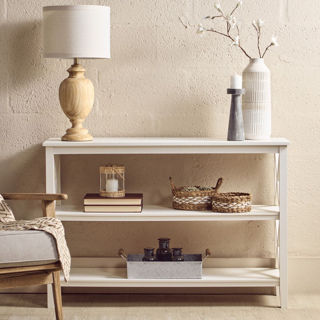 White console table with decorative items against a beige wall
