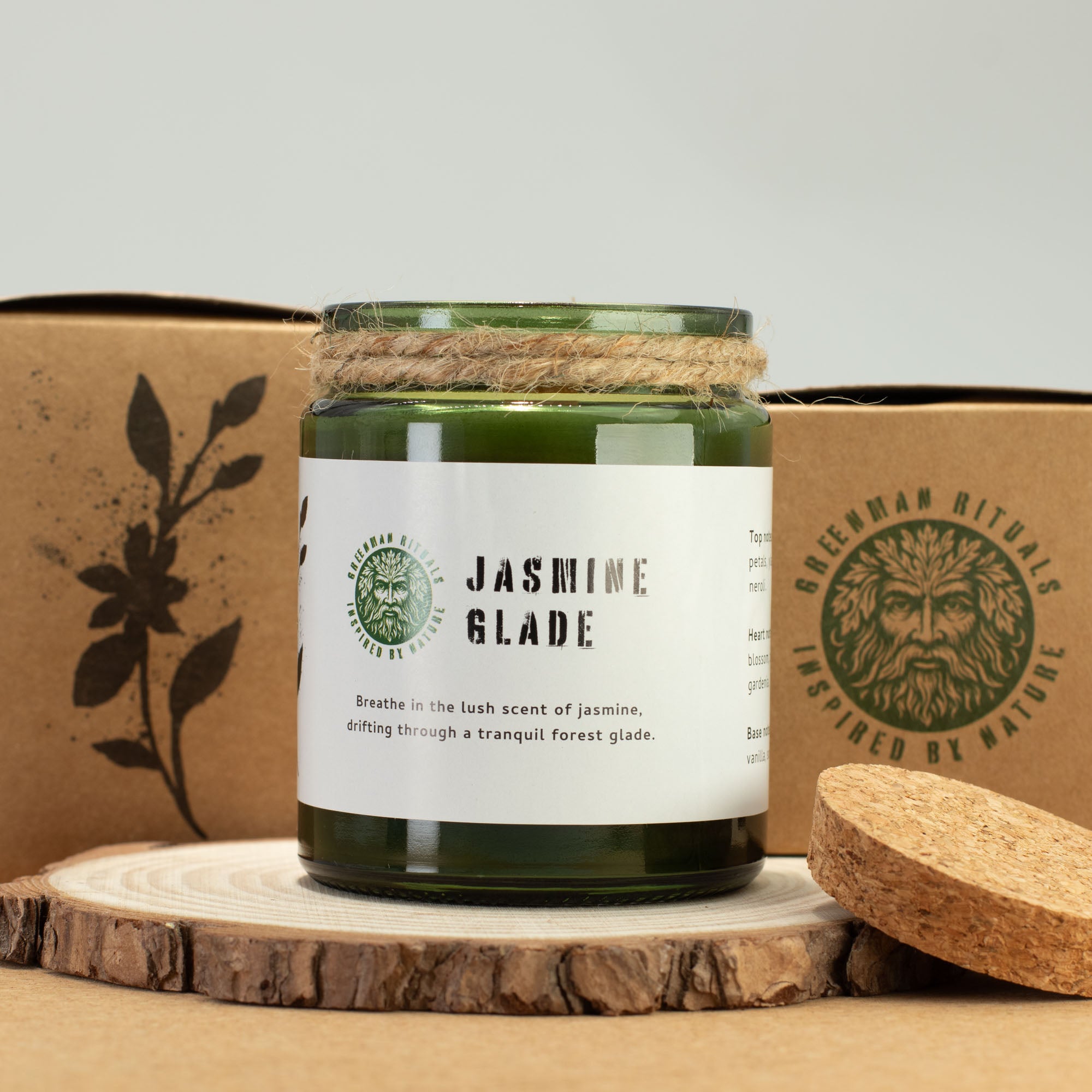 Green candle labeled 'Jasmine Glade' on a wooden surface with a branded box in the background.