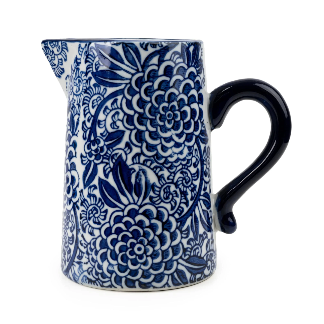 A ceramic pitcher with a blue and white floral pattern, featuring a dark blue handle and spout, set against a plain white background.