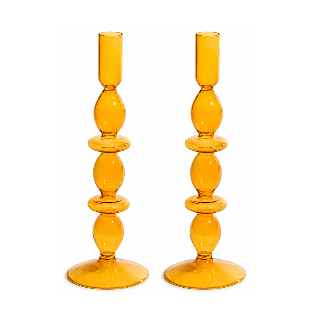 A pair of amber yellow glass candlesticks with a stacked, bulbous design and circular bases, shown on a plain white background.