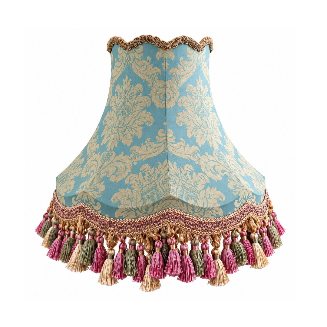 A decorative lampshade with a light blue and beige damask pattern, finished with a scalloped tassel trim at the top and bottom.