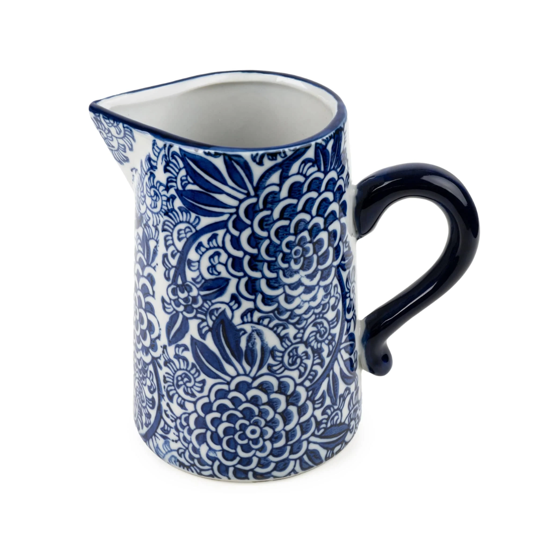 A small ceramic pitcher with a blue and white floral pattern, featuring a dark blue handle and spout, set against a plain white background.