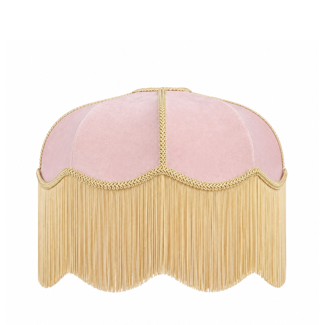 A dome-shaped pink velvet lampshade with a long gold fringe and gold braided trim along the scalloped edge, shown against a plain white background.