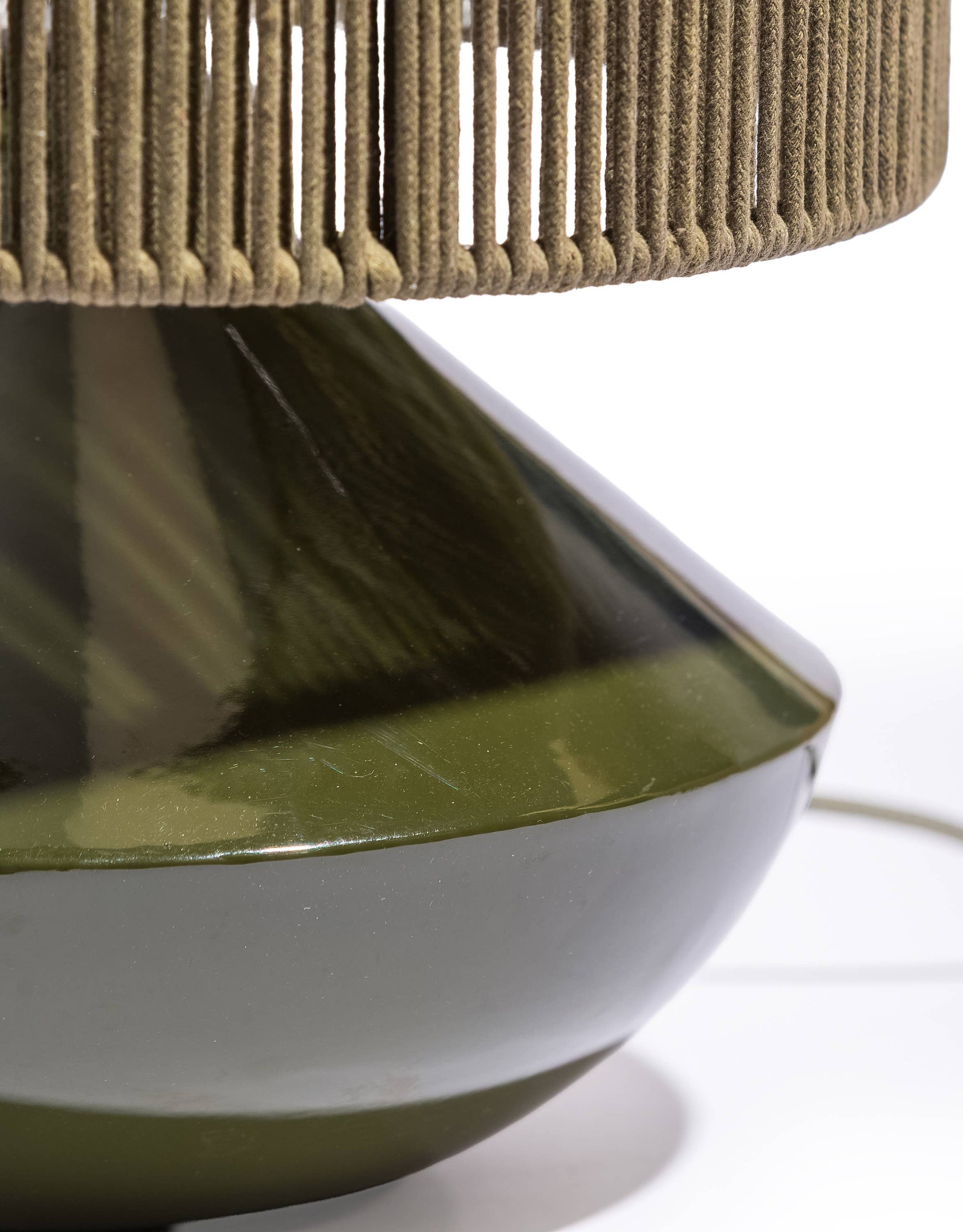 Close-up of a lamp with a woven shade and metallic base on a white background