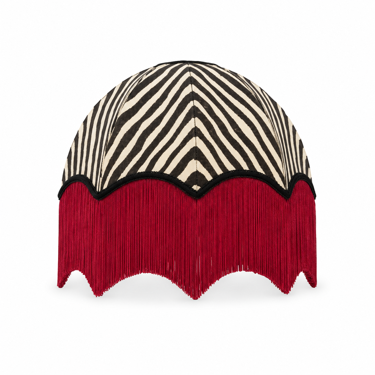A dome-shaped decorative headpiece or hat featuring a black and cream zebra-stripe pattern on the top, a black scalloped border, and a long, dense deep red fringe along the bottom, shown against a plain white background.